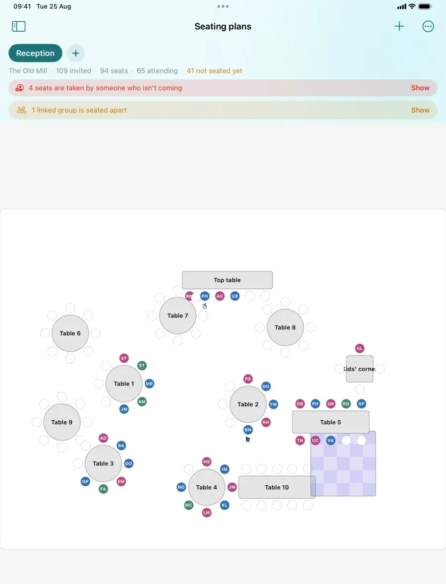 A seating plan on iPad: numbered round tables, a top table and a kids' corner, guests placed in seats, and a warning that some seats are taken by people who are not coming.