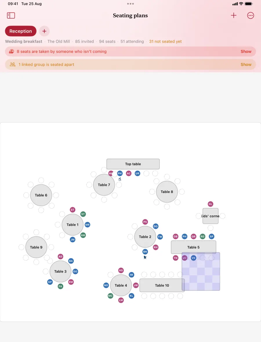A seating plan on iPad: numbered round tables, a top table and a kids' corner, guests placed in seats, and a warning that some seats are taken by people who are not coming.